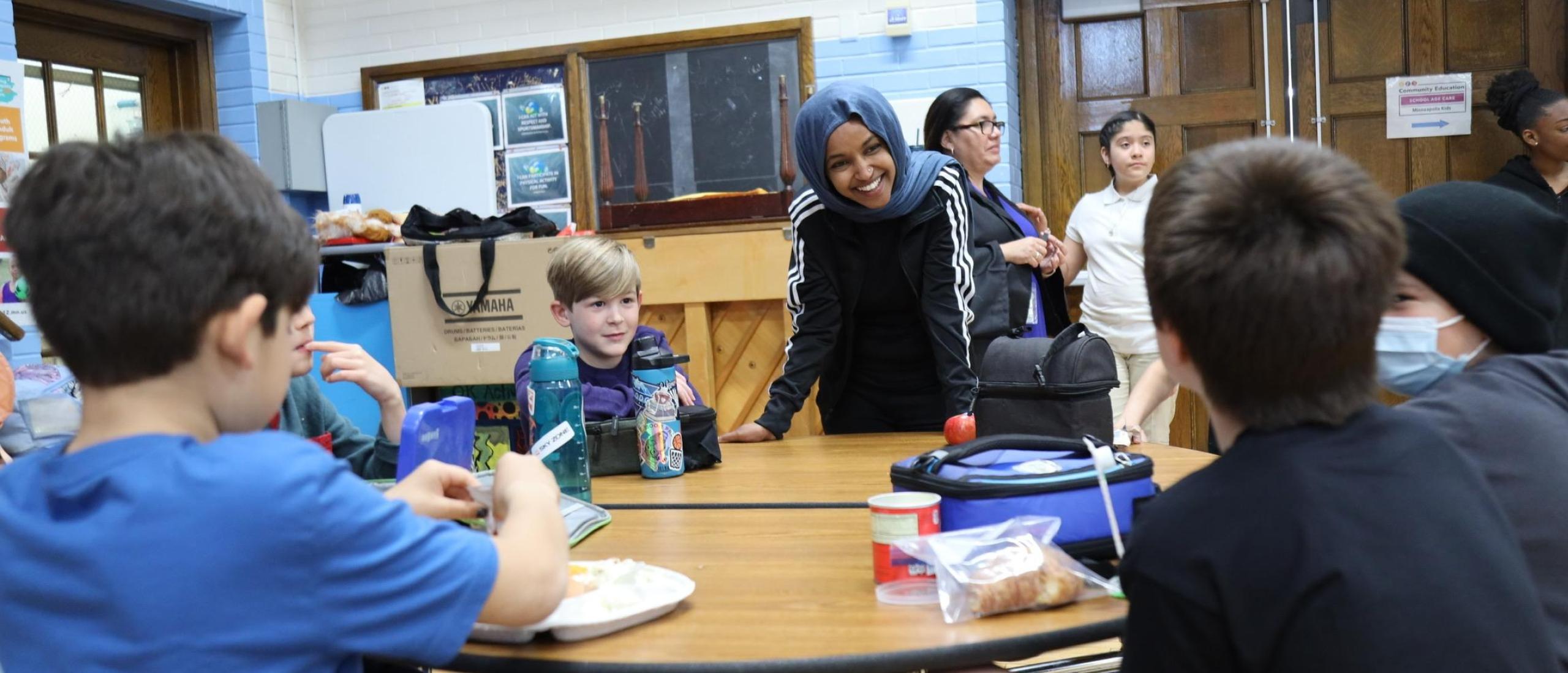 Rep. Omar speaks with elementary school students eating lunch